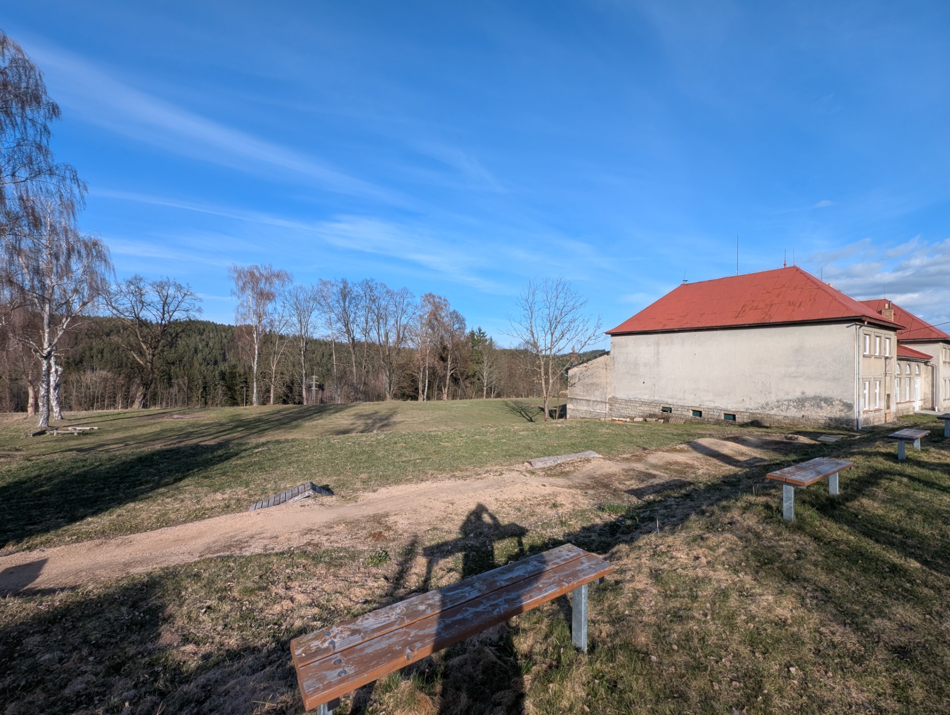 Pod sokolovnou budou parkovat auta, ale vlevo pod břízkami je prostor pro stany.